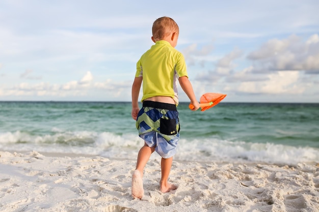 Vista trasera de un niño caminando por la playa