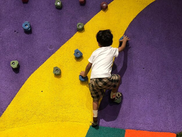 Foto vista trasera de un niño escalando la pared