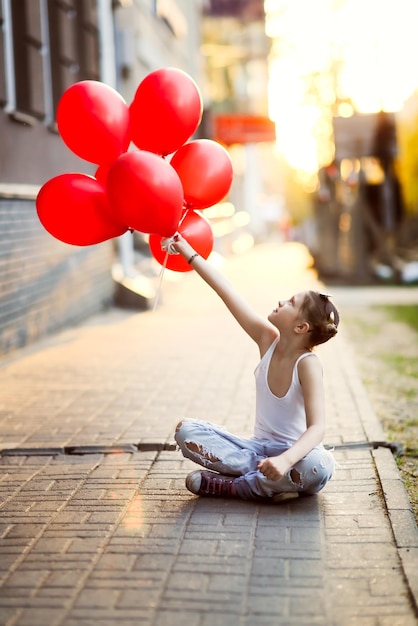 Foto vista trasera de un niño con globos rojos