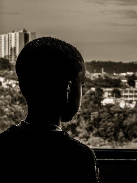 Vista trasera de un niño mirando por la ventana