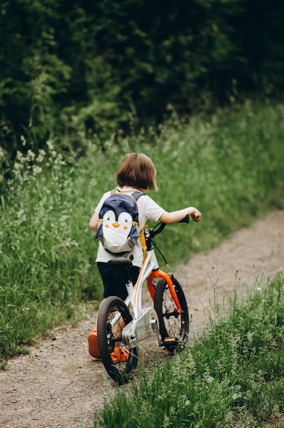 Vista trasera de un niño montando una bicicleta en el campo