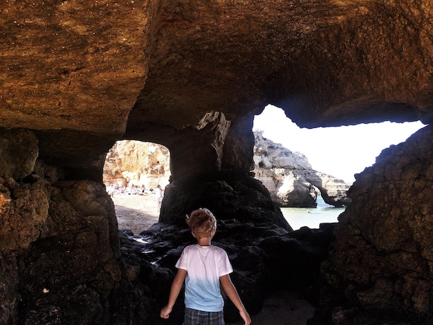 Foto vista trasera de un niño de pie en la cueva