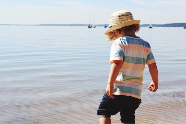 Vista trasera de un niño de pie en el lago