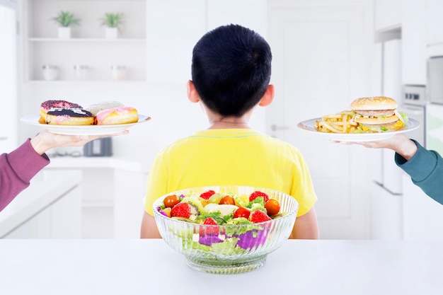 Vista trasera del niño que se niega a comer en la cocina