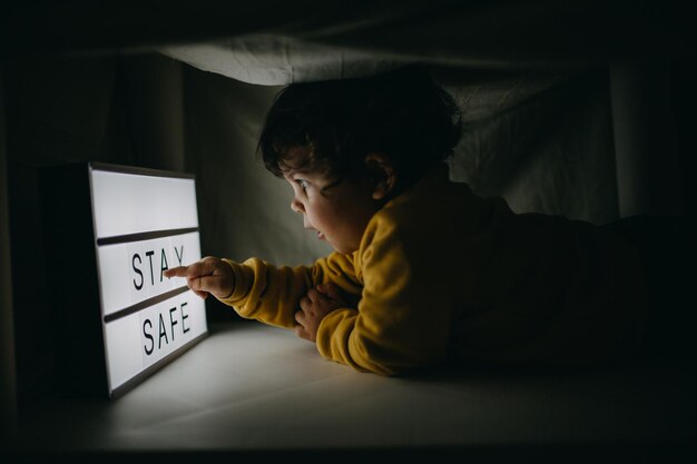 Foto vista trasera de un niño sentado en la cama en casa
