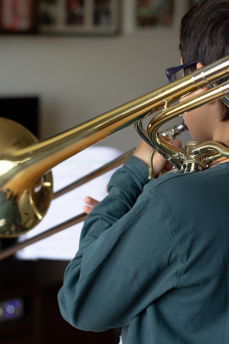 Foto vista trasera de un niño tocando la trompeta en casa