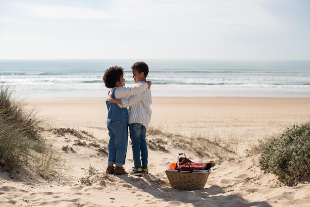 Vista trasera de niños afroamericanos contentos. Hermano y hermana con ropa informal mirándose, abrazándose. Retrato, familia, concepto de infancia.