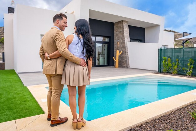 Vista trasera de una orgullosa pareja contemplando su casa recién comprada