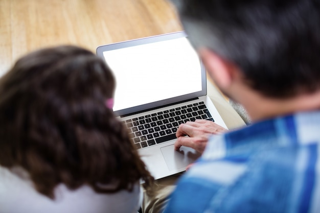 Vista trasera del padre y la hija usando laptop