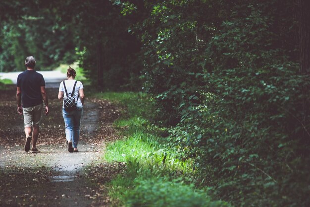 Foto vista trasera de una pareja caminando por la carretera en el bosque