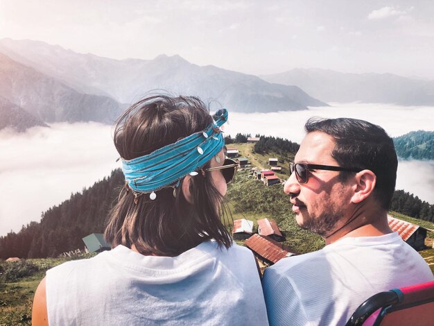 Vista trasera de la pareja contra las montañas y el cielo