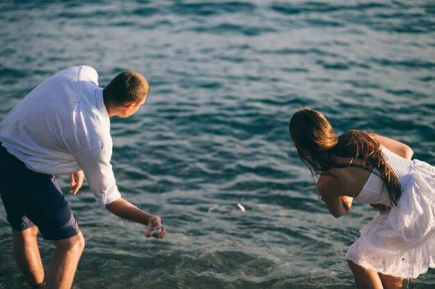 Foto vista trasera de una pareja desnatando piedras en el lago