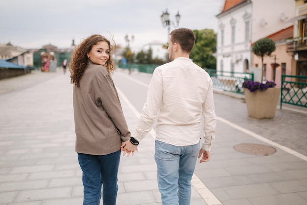 Vista trasera de una pareja feliz caminando por la ciudad Mujer joven atractiva y hombre joven guapo en el centro de la ciudad Gente sonriente