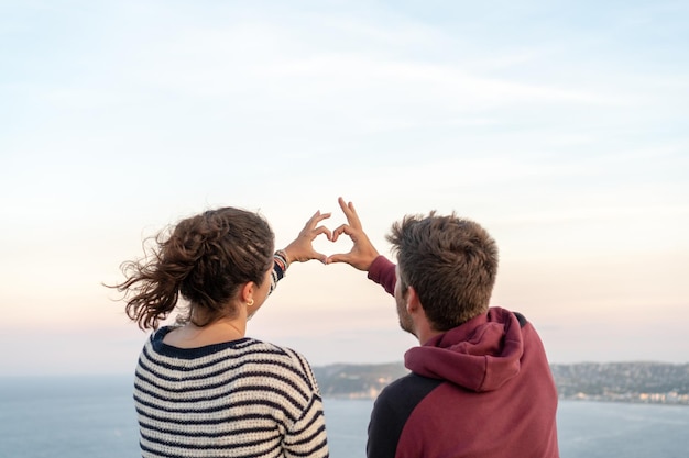 Vista trasera de una pareja haciendo la forma de un corazón