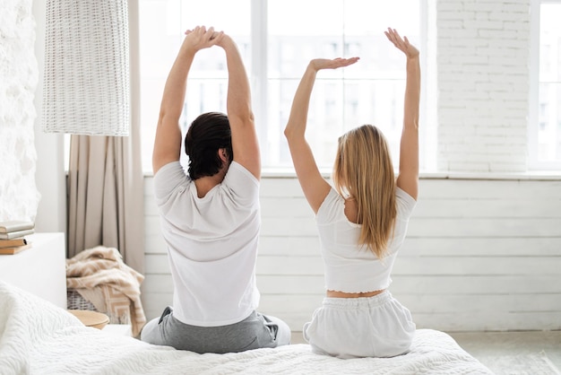 Vista trasera de una pareja joven que se estira en la cama después de despertarse en casa