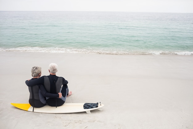 Vista trasera de la pareja sentada en la tabla de surf