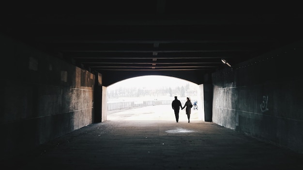 Vista trasera de una pareja de siluetas caminando en un túnel