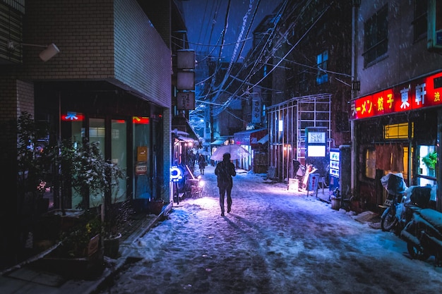 Foto vista trasera de una persona caminando por una calle iluminada en la ciudad por la noche