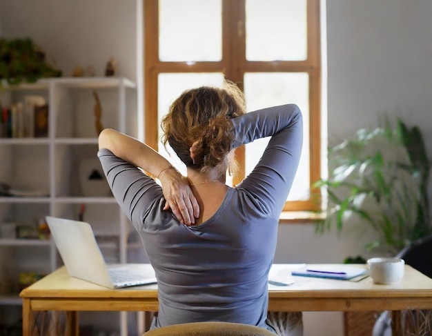 Vista trasera de una persona de mediana edad en una sala de estudio manteniendo una postura ergonómica adecuada abordando dis...