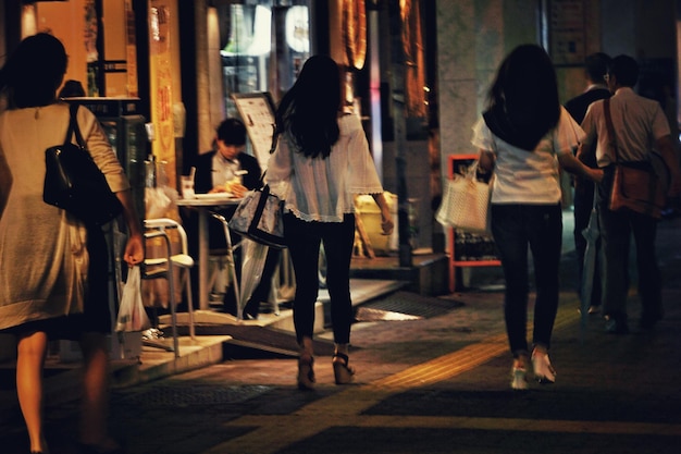 Vista trasera de personas caminando por la calle por la noche