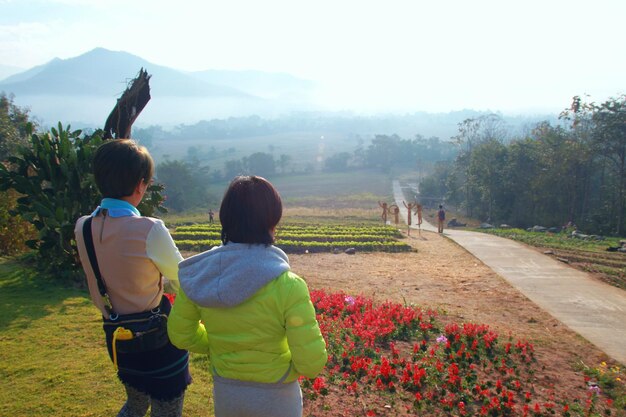 Foto vista trasera de personas de pie en el campo de flores