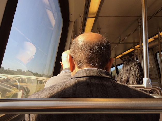 Vista trasera de personas sentadas en el tren durante un día soleado