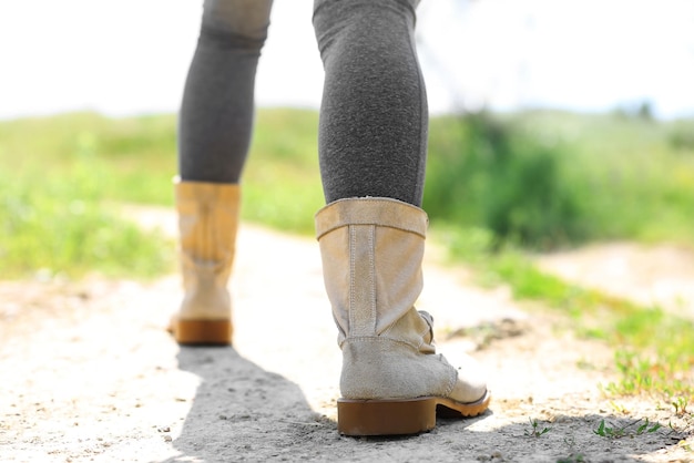 Vista trasera de las piernas de una excursionista con botas subiendo la colina en un día soleado