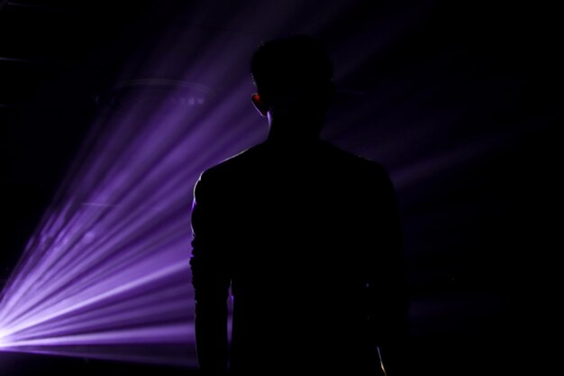 Vista trasera de la silueta del hombre de pie contra la luz iluminada