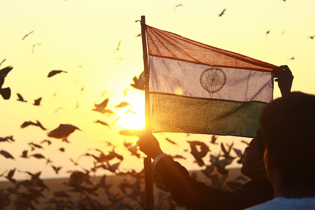 Vista trasera de la silueta de un hombre sosteniendo la bandera de la India contra el cielo durante la puesta del sol