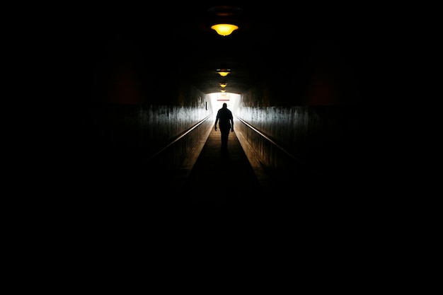 Foto vista trasera de la silueta de una mujer caminando en un túnel