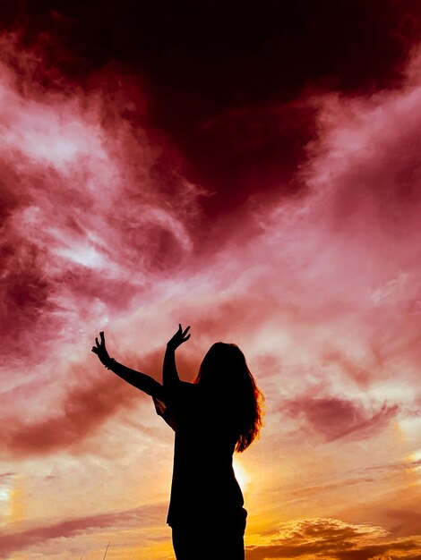 Foto vista trasera de la silueta de una mujer de pie contra el cielo durante la puesta de sol