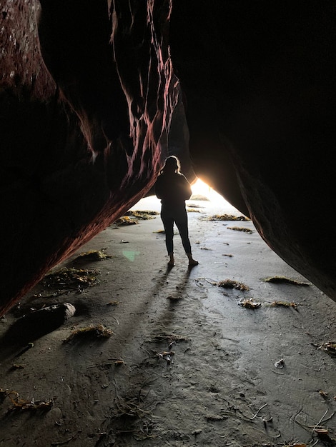 Foto vista trasera de la silueta de una mujer de pie en la cueva