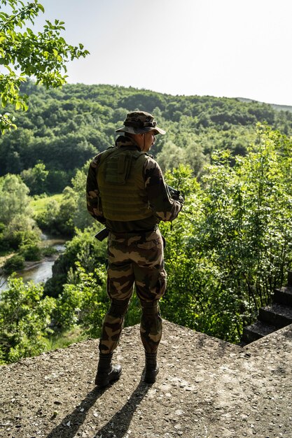 Foto vista trasera del soldado de pie contra los árboles