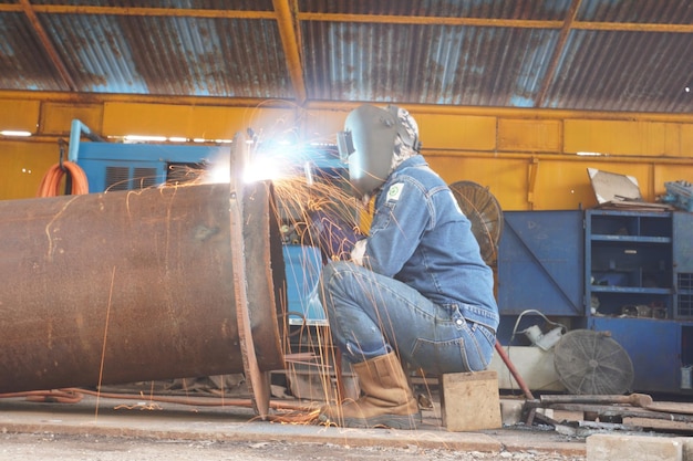 Foto vista trasera de un soldador trabajando en actividades de soldadura en un taller de soldadura