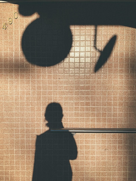 Foto vista trasera de la sombra de la mujer de pie contra la pared