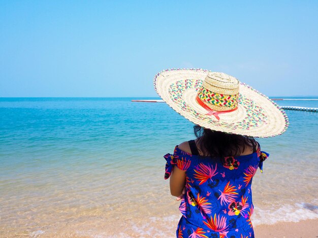 Vista trasera del sombrero de la mujer en la playa contra el cielo