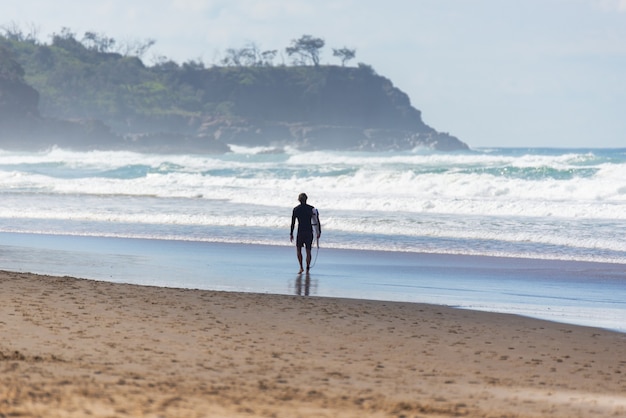 Vista trasera del surfista caminando en una playa australiana en Summer.Water Deport Concept.listro