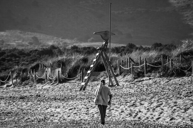 Foto vista trasera a toda longitud de un hombre caminando por una playa de arena