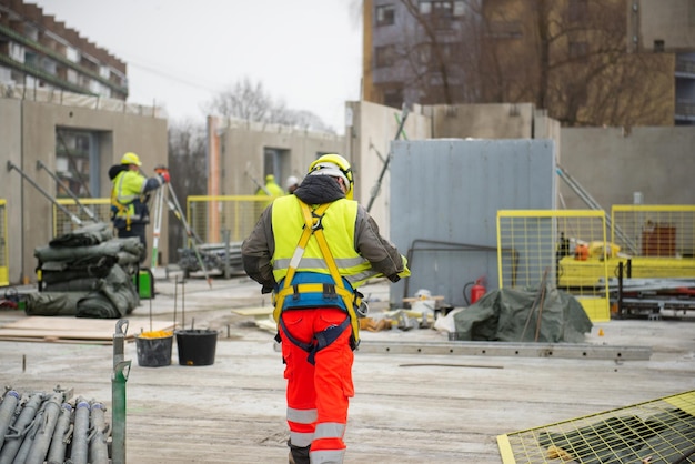 Vista trasera de un trabajador de la construcción masculino en el sitio de construcción con casco y chaleco de alta visibilidad