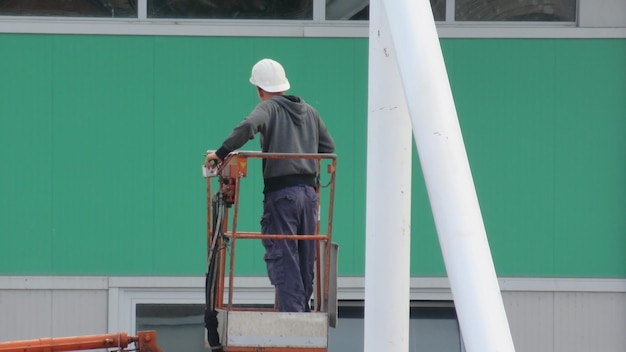 Foto vista trasera de un trabajador de la construcción de pie en un recolector de cerezas contra el edificio