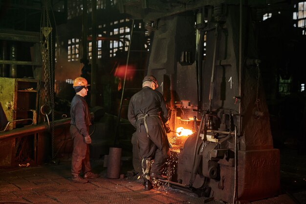 Vista trasera de los trabajadores que trabajan con metal en planta industrial