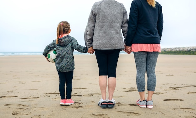 Vista trasera de tres generaciones de mujeres mirando el mar en otoño