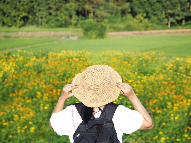 Vista trasera del turista mujer mirando el campo de flor amarilla