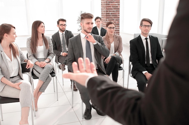 Vista traseraentrenador de negocios gesticulando su mano frente a un grupo de personas