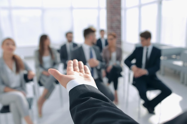 Vista traseraEntrenador de negocios gesticulando con su mano frente a un grupo de personascerrar