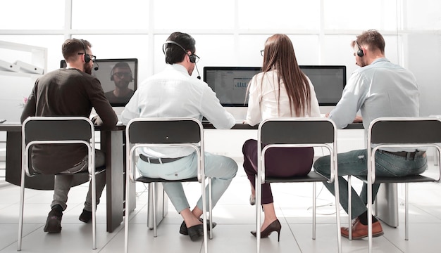 Foto vista traseraun grupo de personas en los auriculares trabaja en una oficina moderna