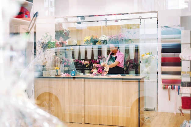 Foto una vista a través de la ventana de una floristería y una florista haciendo ramos