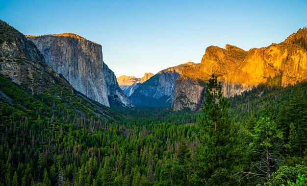 Foto vista del túnel en yosemite al atardecer con montañas iluminadas y un cielo azul