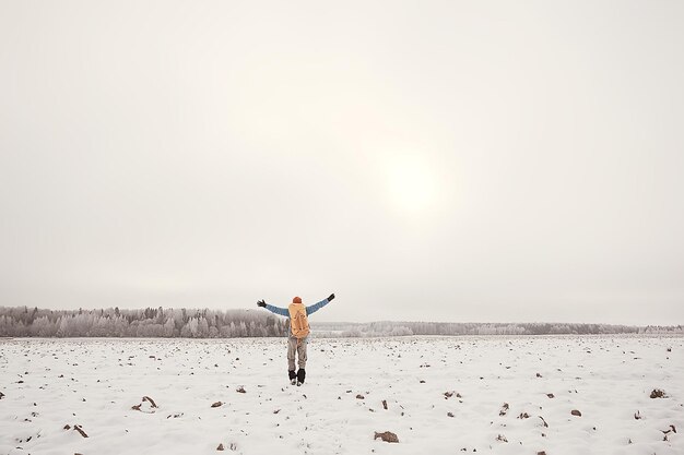 vista turística da parte de trás / um homem com uma mochila atravessa a floresta de inverno, vista da saída