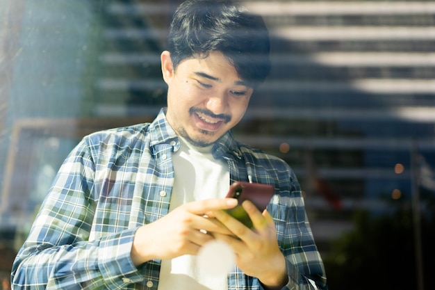 Vista desde el vaso de café en la mano del hombre de Oriente Medio con smartphone para reproducir redes sociales